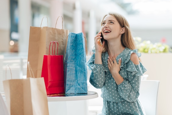 Mulher feliz saindo de uma loja com sacolas de compras